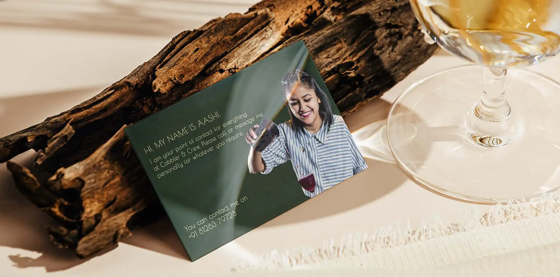 Cobbler and Crew visiting card on a wood piece with cocktail